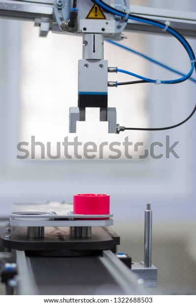 Industry 4.0 concept; artificial intelligence in\
production. Focus on the gripper. Gripper picks up product from\
automated car on the automated production line in a smart factory.\
Selective focus.