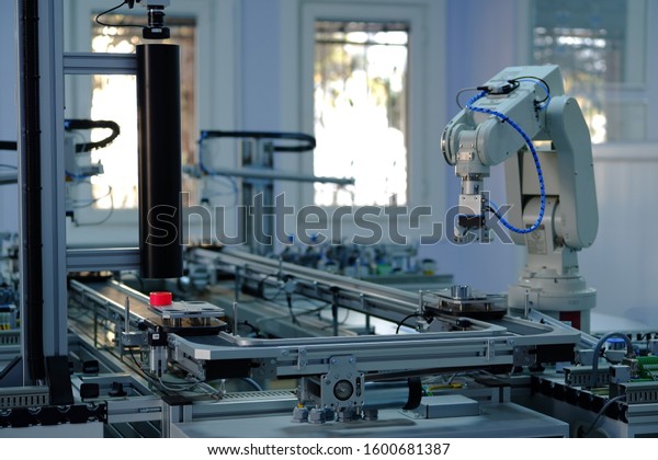 Industry 4.0 concept; artificial intelligence in\
smart factory prototype. Robot picks up the product from automated\
car on the manufacturing line. Focus on robotic arm\'s gripper.\
Selective focus.