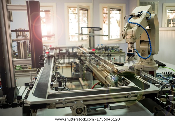 Industry 4.0 concept; artificial intelligence in\
smart factory prototype. Robot picks up the product from automated\
car on the manufacturing line. Focus on robot arm\'s gripper.\
Selective focus.