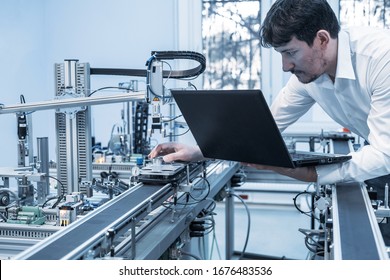 Industry 4.0 concept; Engineer is working on laptop to program smart factory prototype's automation. automated car on production line,  artificial intelligence in smart manufacturing. - Shutterstock ID 1676483536