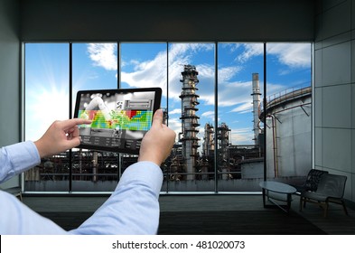 Industry 4.0 Concept .Man Hand Holding Tablet With Augmented Reality Screen And Automate Wireless Robot Arm Software At Industrial Room In Smart Factory.Window Showing Oil Refinery Industry Background