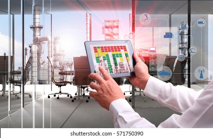 Industry 4.0 Concept .Man Hand Holding Tablet With Augmented Reality Screen And Automate Wireless Robot Arm Software At Industrial Room In Smart Factory.Window Showing Oil Refinery Industry Background