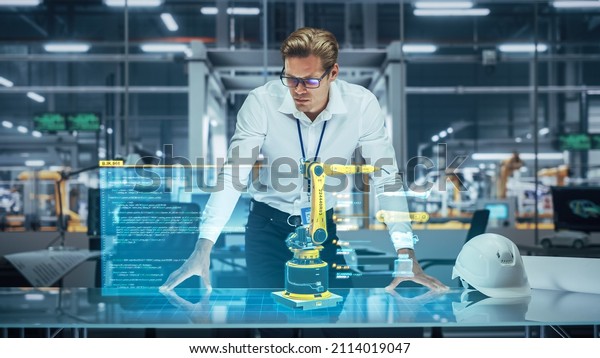 Industry 4.0 High-Tech Factory: Robotics\
Engineer Working on Robot Arm Design, Using Augmented Reality\
Hologram to Analyze Conceptual 3D Model. Futuristic Engineering\
with Digital\
Technology