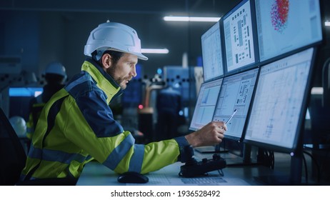 Industry 4.0 Modern Factory: Facility Operator Controls Workshop Production Line, Uses Computer with Screens Showing Complex UI of Machine Operation Processes, Controllers, Machinery Blueprints