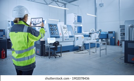 Industry 4.0 Modern Factory: Female Engineer Uses Digital Tablet Computer With Augmented Reality To Visualize Workshop Mapping, Floor Layout. Facility With High-Tech CNC Machinery And Robot Arm