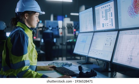 Industry 4 0 Modern Factory: Female Facility Operator Controls Workshop Production Line  Uses Computer and Screens Showing Complex UI Machine Operation Processes  Controllers  Machinery Blueprints