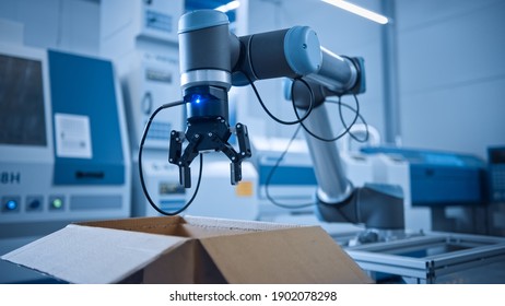 Industry 4.0 Modern Factory: Programmed Robot arm Packing Metal Components into Cardboard Box. Production Line Machine Picks Packs Product into Package on Conveyor. Fully Automated Warehouse Robotics - Shutterstock ID 1902078298