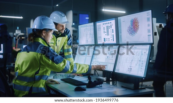 Industry 4.0 Modern Factory: Project Engineer Talks to Female Operator who Controls Facility Production Line, Uses Computer with Screens Showing AI, Machine Learning Enhanced Assembly Process