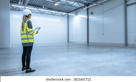 Industry 4.0 Modern Warehouse: Female Engineer in Empty Warehouse Uses Digital Tablet Computer with Augmented Reality Software for Future Factory or Warehouse Layout. Concept Shot of Augmented Reality