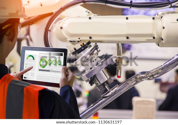 Industry 4.0 Robot concept\
.Engineers use laptop computers for machine maintenance, automation\
tools, .Close up of a robot arm in a car manufacturing\
department.\
