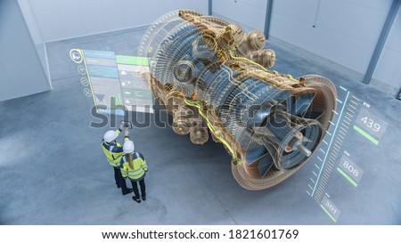 Industry 4.0 Two Engineers Standing and Talking in Factory Workshop with Augmented Reality 3D Model Concept of Giant Turbine Engine. Graphics Visualization. High Angle Shot. VFX Special Visual Effects Stockfoto © 