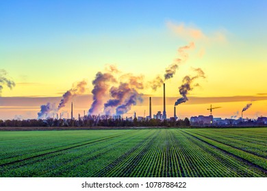 industry complex in Frankfurt in early morning with green fields and smoking chimney