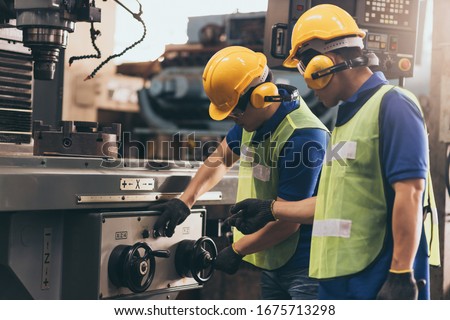 Industry engineer team worker teaching help talking production machine and setting it for work in modern factory. staff operate control heavy machine in factory