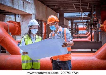 Industry engineer under checking the industry cooling tower air conditioner water cooling tower air chiller HVAC of large industrial building to control air system,wearing mask to protect pollution.