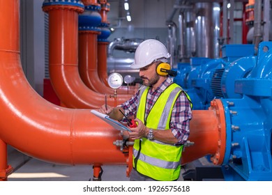 Industry engineer worker wearing safety uniform under checking the industry cooling tower air conditioner is water cooling tower air chiller HVAC of large industrial building to control air system.