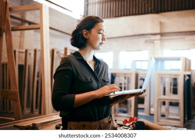 Industry, laptop and typing with carpenter woman in workshop for craftsmanship, joinery or woodworking. Computer, inventory and online order with confident person in warehouse for carpentry or trade - Powered by Shutterstock