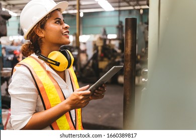 Industry maintenance engineer woman dark skin wearing uniform and safety helmet under inspection and checking production process on factory station by tablet. Industry, Engineer, construction concept. - Powered by Shutterstock