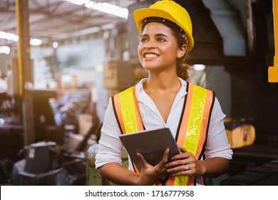 Industry maintenance engineer woman dark skin wearing uniform and safety helmet under inspection and checking production process on factory station by tablet. Industry, Engineer, construction concept.