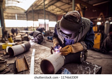 Industry male worker in protective uniform repairing metal pipe.