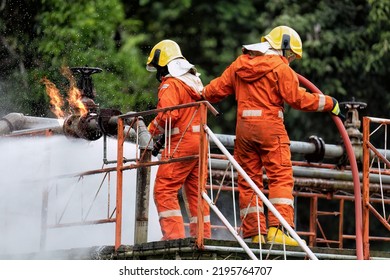 In Industry Plant Fire Fighter Team On  Training Fight With Gas And Oil Fire From The Pipe Line And Valves By Hold Hose Spray Jet Turbulence Water And Foam And Continue Spray Water To Extinguish