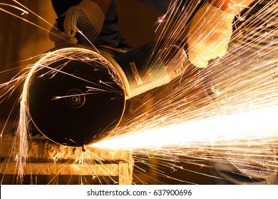 Industry worker cutting metal with grinder. Lots of glowing sparks