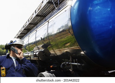 industry worker, driver talking in phone, large fuel-truck in the background