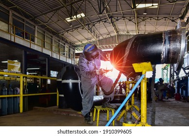 Industry worker at the factory welding big steel pipe by TIG Welder