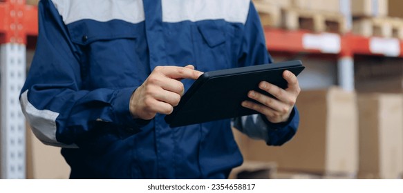 Industry worker use computer tablet in logistic warehouse with cardboard boxes for delivery. Banner online deliver cargo business.