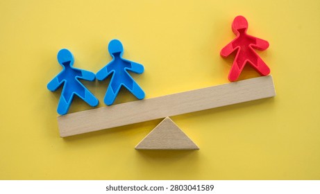 Inequality and leverage concept with two blue figures outweighed by a single red figure on a wooden seesaw