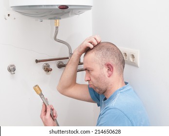 Inexperienced plumber trying to repair an electric water heater - Shutterstock ID 214650628
