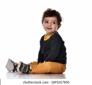 Infant Baby Boy Toddler In White Bodysuit Is Sitting Sideways On The Floor Looking Up At Us On A Gray Background With Free Text Copy Space.