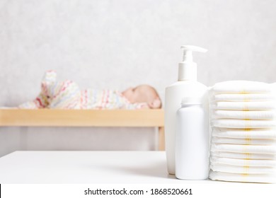 Infant Baby Care Products. Lotion, Powder And Diapers On Changing Table In Nursery. Baby Cosmetics And Hygiene Concept.