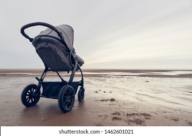 A infant baby childs stroller pushchair pram on a vast beach landscape at dusk and dawn. Relaxing and taking a holiday with children. Bonding travel with family in the great outdoors. - Shutterstock ID 1462601021