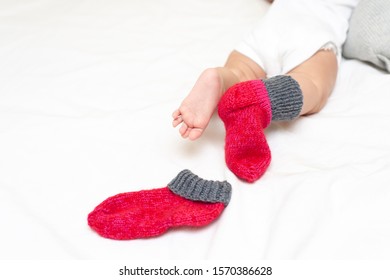 Infant Baby In One Red Sock A White Background. Concept Of Winter, Hug, Cozy, Hygge.