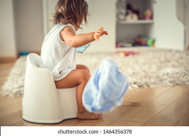 Infant child baby girl toddler sitting on potty training seat, using a smartphone. (age 1,5 years)