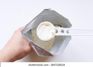 Infant Formula. Dry Formula For Feeding The Baby In A Spoon. Hand With A Spoon Filled With Infant Formula Over The Package.