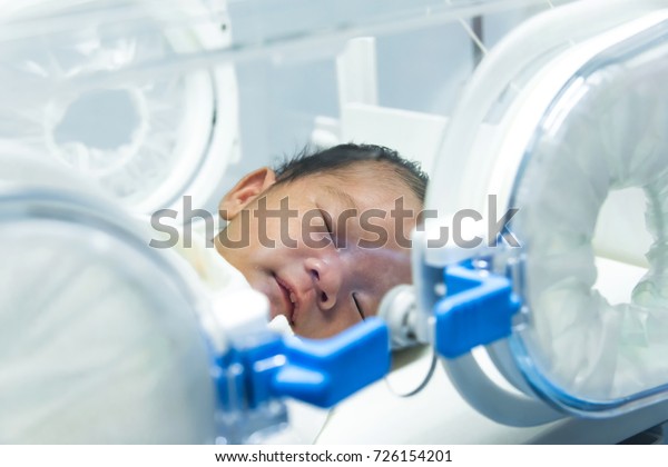 Infant in incubator machine maintain healthy
environment for newborn premature sick babies neonatal intensive
care unit.