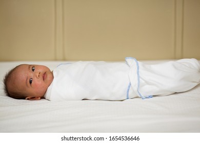 infant on the bed looking at the camera