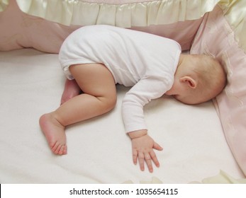 The Infant In White Clothes Is Sleeping, Lying On His Stomach, In His White Crib. Baby Is Sleeping Face Down