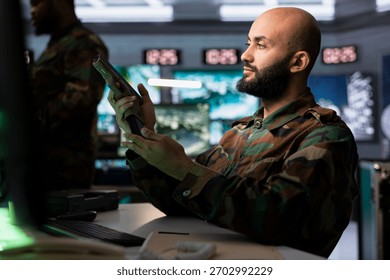 Infantry unit in command post putting ammunition in pistol cartridge, preparing to attack enemy forces. Middle Eastern army soldier reloading handgun, preparing to start assault mission