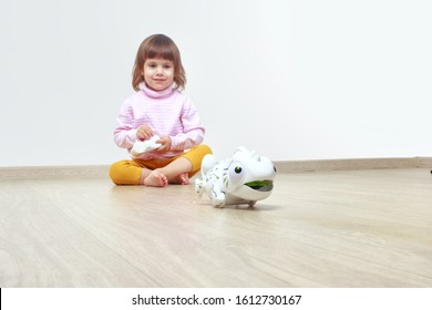 Infatuated Cute Little Girl Playing Plastic Toy Lizard Robot With A Remote Control. The Nano-toy Chameleon, Modern Technology Of Toys. Electronic Pet.