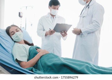 Infected patient woman with face mask lying in bed at disease treatment room, doctor wearing protective clothing  take care of the sick in quarantine at hospital - Shutterstock ID 1755896279