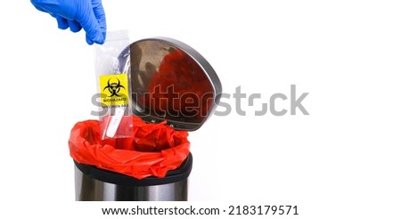 Infectious garbage is being thrown into the red infectious waste bin by the doctor hand with a copy space on white background 