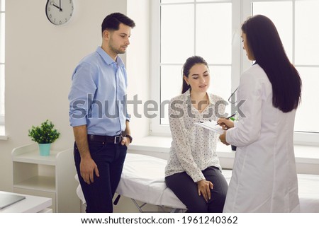 Infertility problem cure at clinic. Young childless family couple consulting with doctor getting prescription discussing treatment plan during appointment in hospital examination chamber