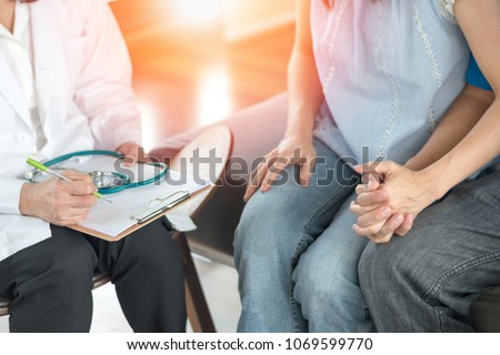 Infertility problem with marriage couple concept. A fertility doctor or reproductive endocrinologist with man and women holding hand together in therapy consult session  of inability to pregnant.