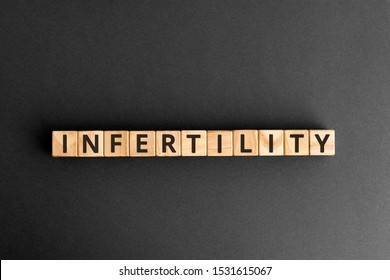 Infertility - word from wooden blocks with letters, inability to become pregnant infertility concept,  top view on grey background