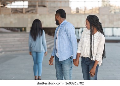 Infidelity concept. Black millennial guy distracted to another woman while walking with his girlfriend in city, selective focus
