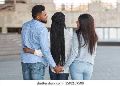 Infidelity concept. Unfaithful african man embracing with girlfriend and holding hand with another lady, cheating his woman with her best friend - Powered by Shutterstock