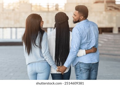 Infidelity concept. Unfaithful african man embracing with girlfriend and holding hand with another lady, cheating his woman with her best friend - Powered by Shutterstock