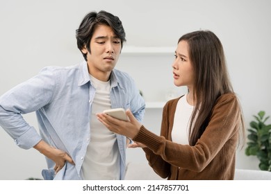 Infidelity, Suspicion Asian Young Couple Love Fight Relationship, Wife Holding A Cellphone. Distrust And Jealousy When Sitting At Home.